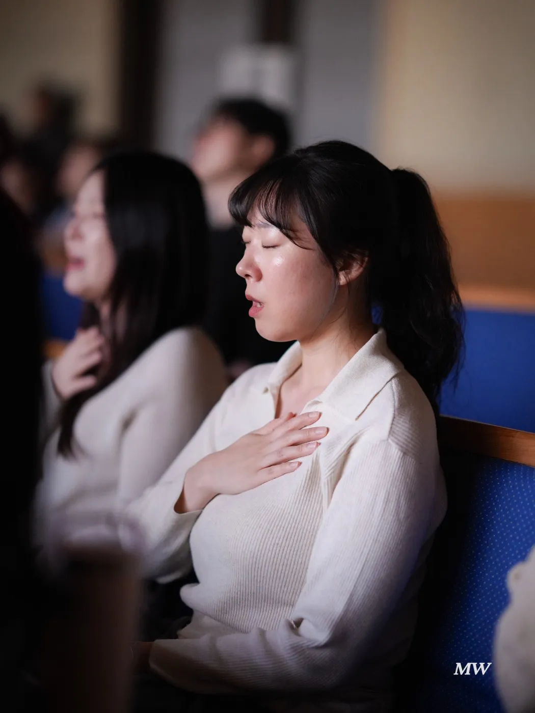 Worshipers with hands on their hearts and eyes closed