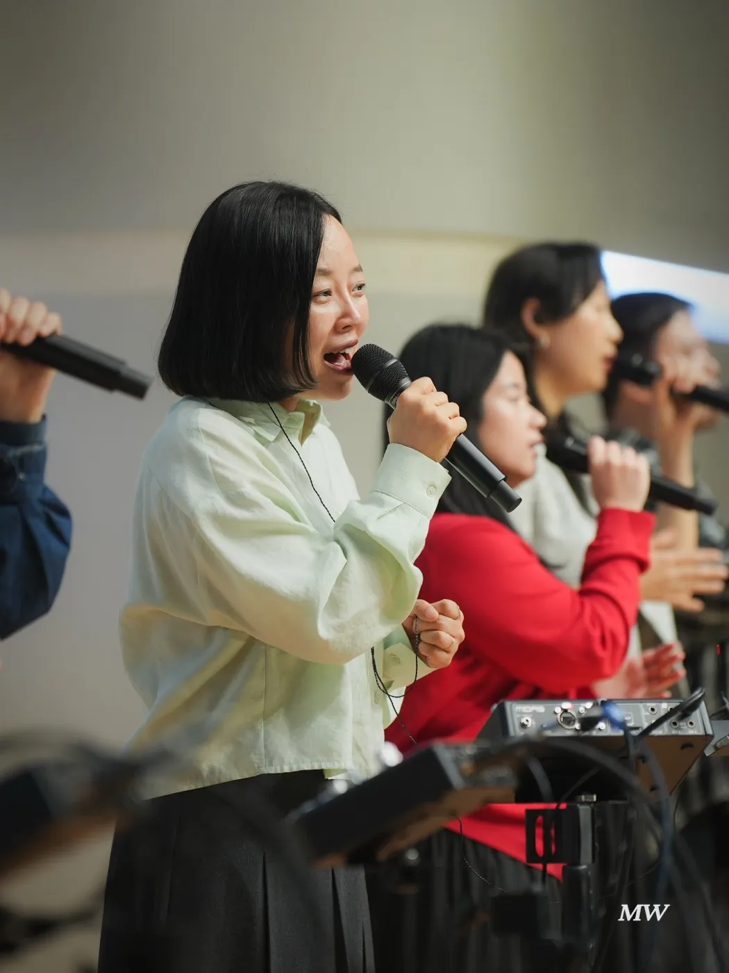 Vocalists singing into microphones on stage