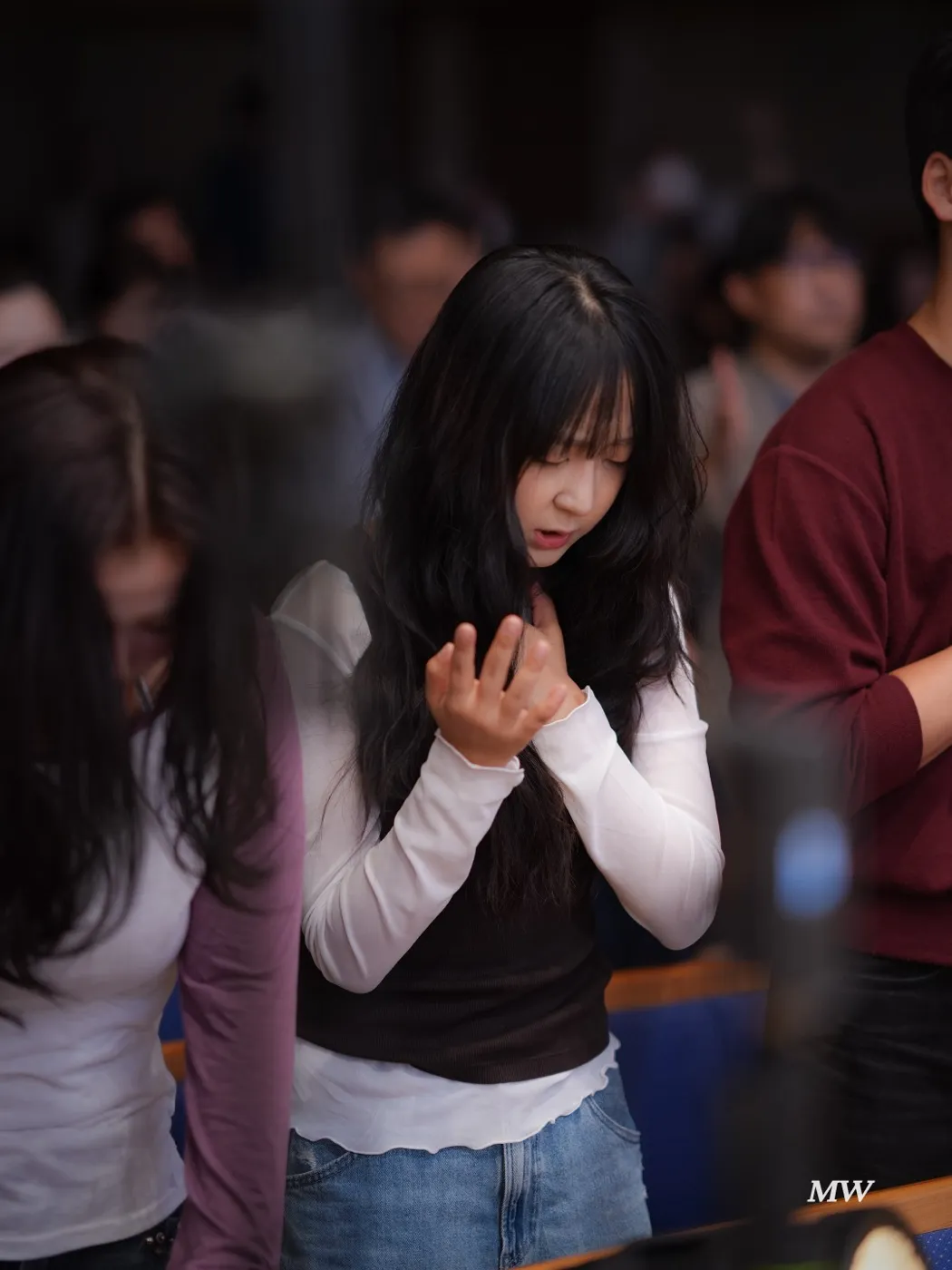 A worshiper singing with hands clasped