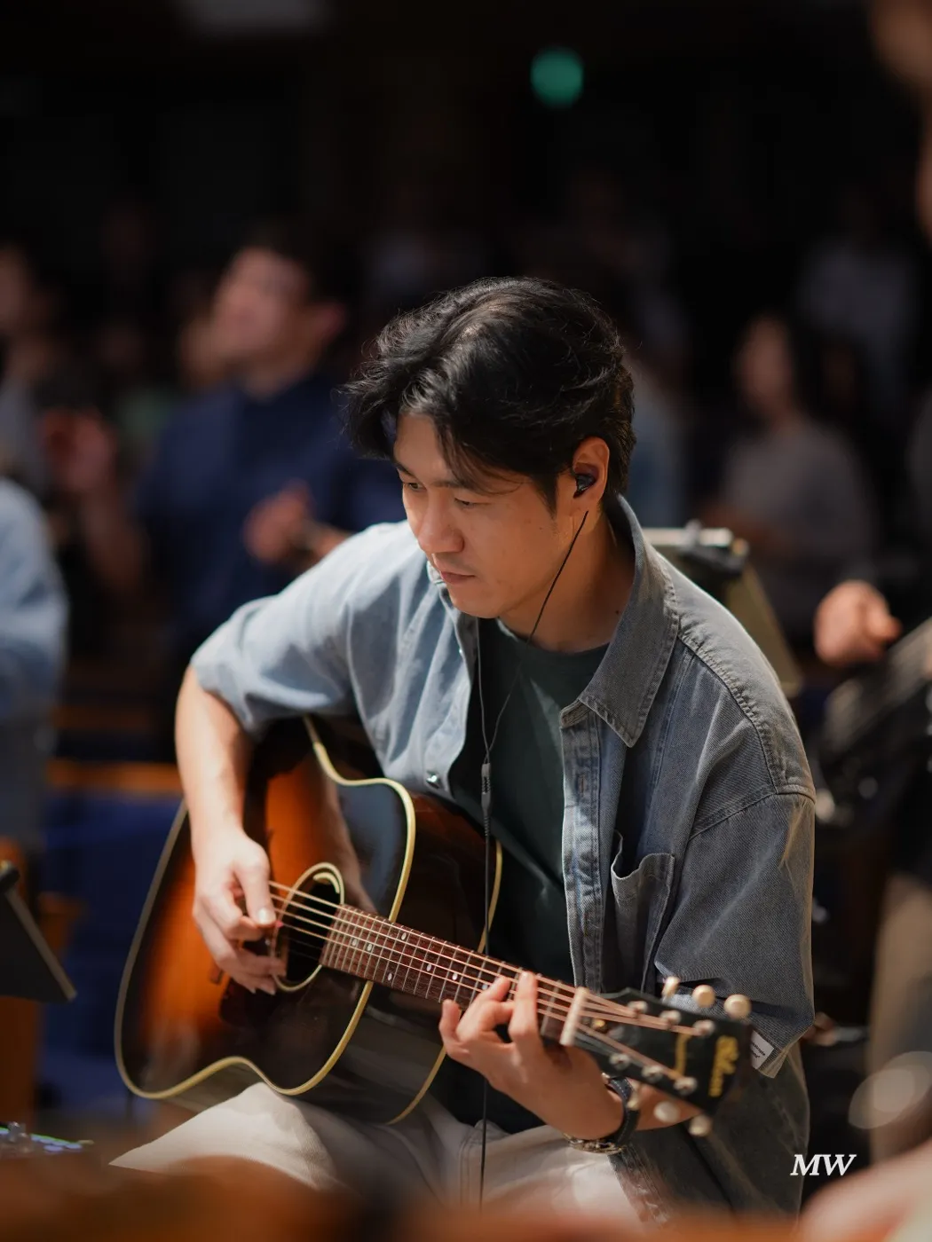 A worship leader singing and playing acoustic guitar