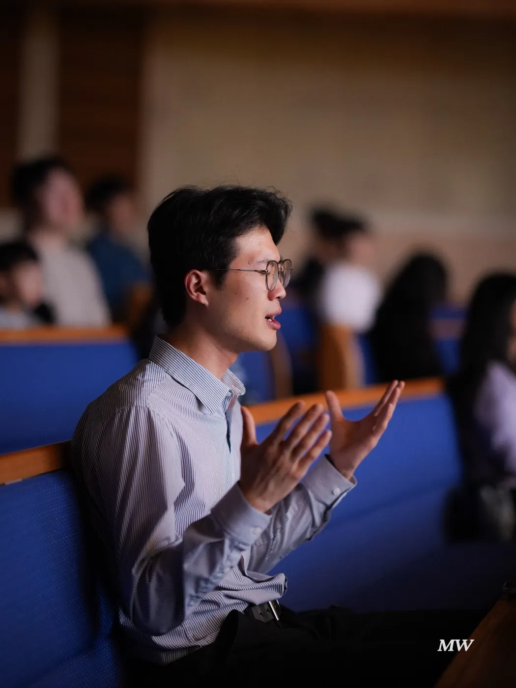 A worshiper in the seats singing with both hands open