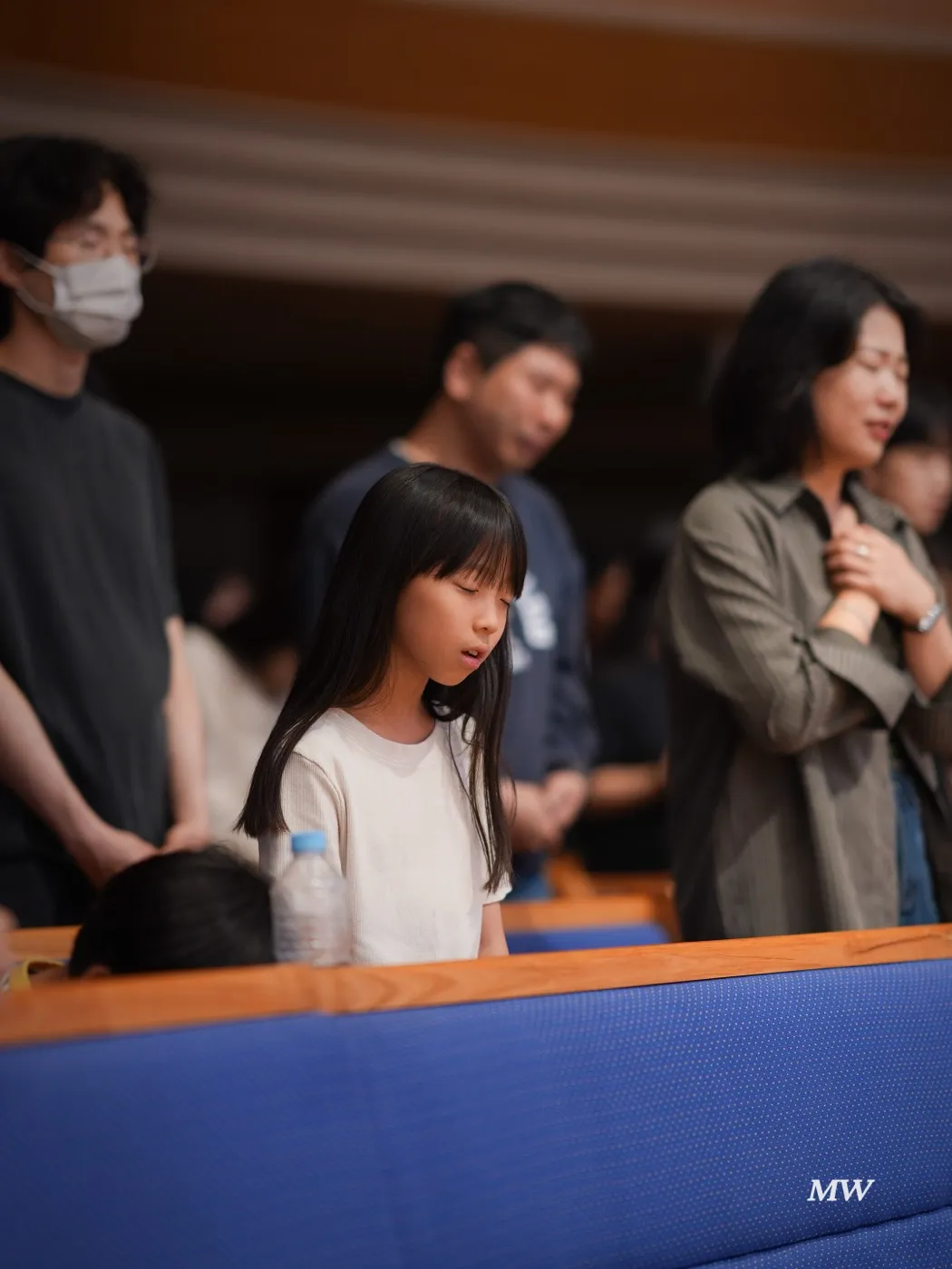 A family standing in worship with their child