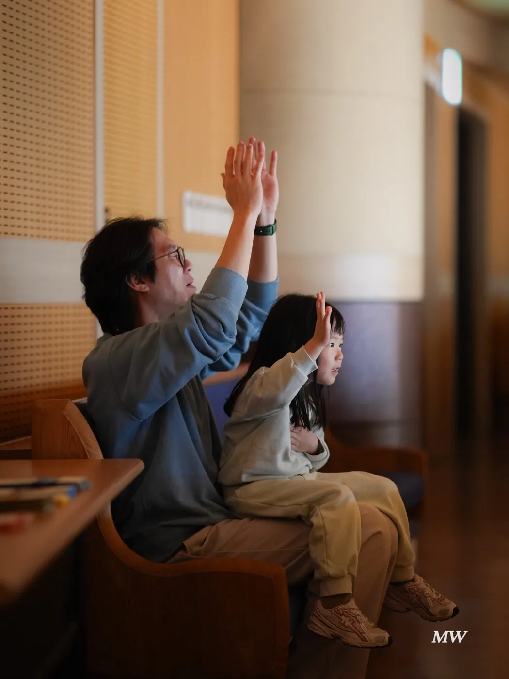 A worshiper with a child on their lap, raising both hands