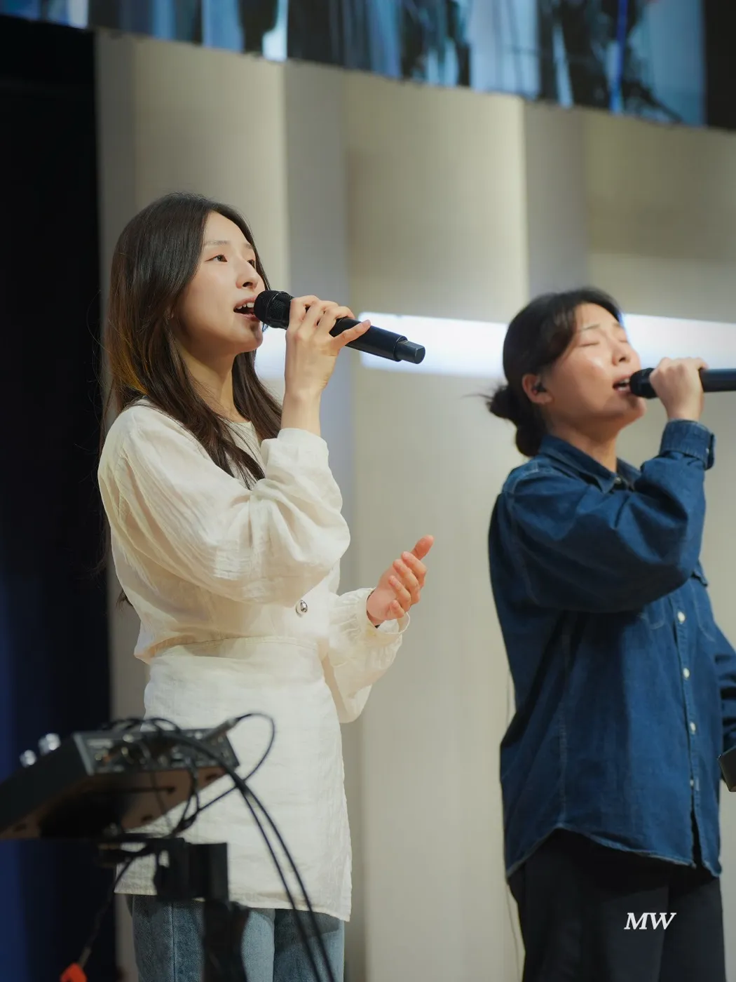 Two vocalists singing into microphones