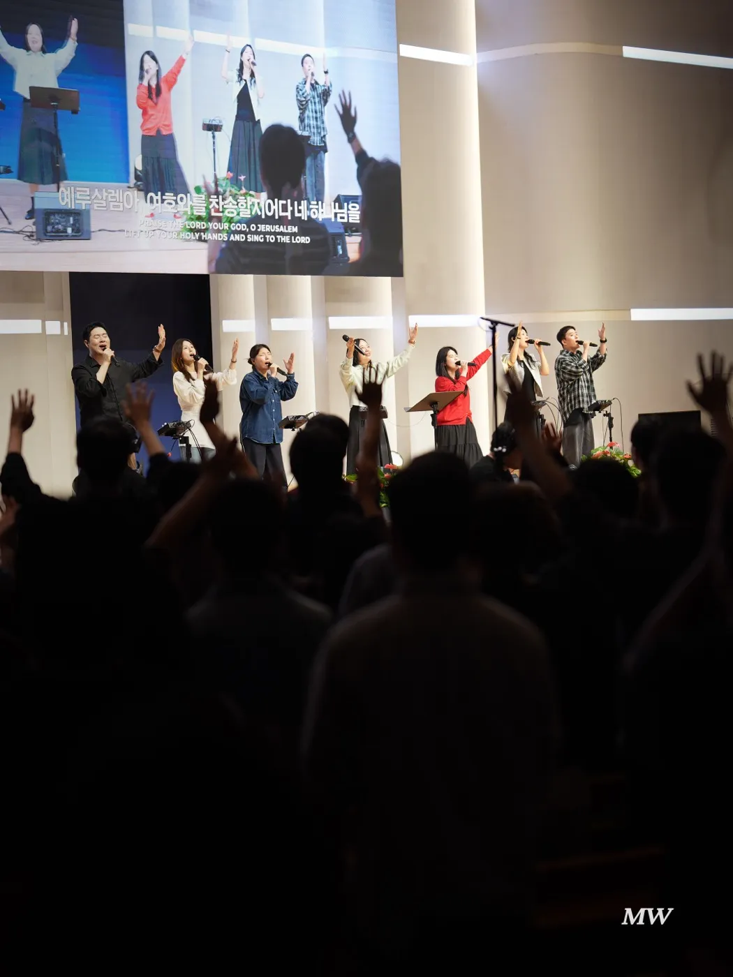 The congregation raising hands, with the worship team on stage