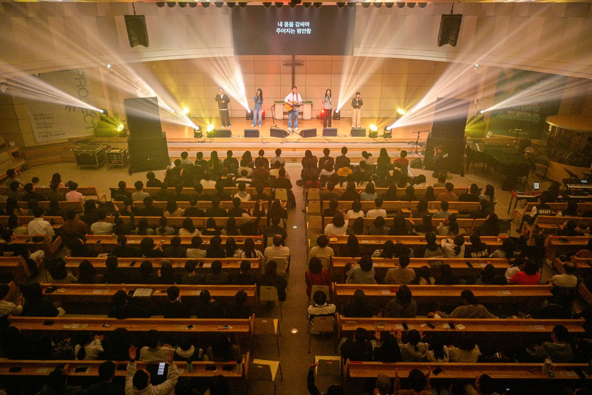 White beams of light from the stage, the congregation seated on both sides of the center aisle